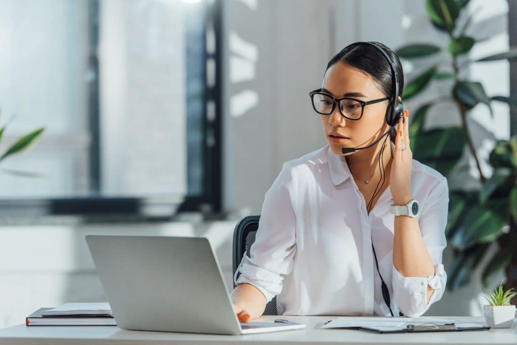 Dolmetscherin mit Headset am Laptop beim Videodolmetschen